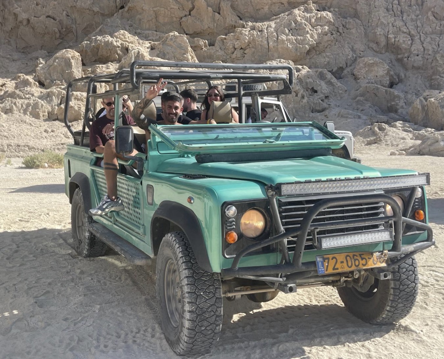 A group waving from a 4x4 jeep on the desert trail